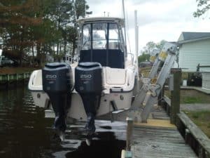 White flats boat secured above the water on IMM Quality boat lift with dock installation